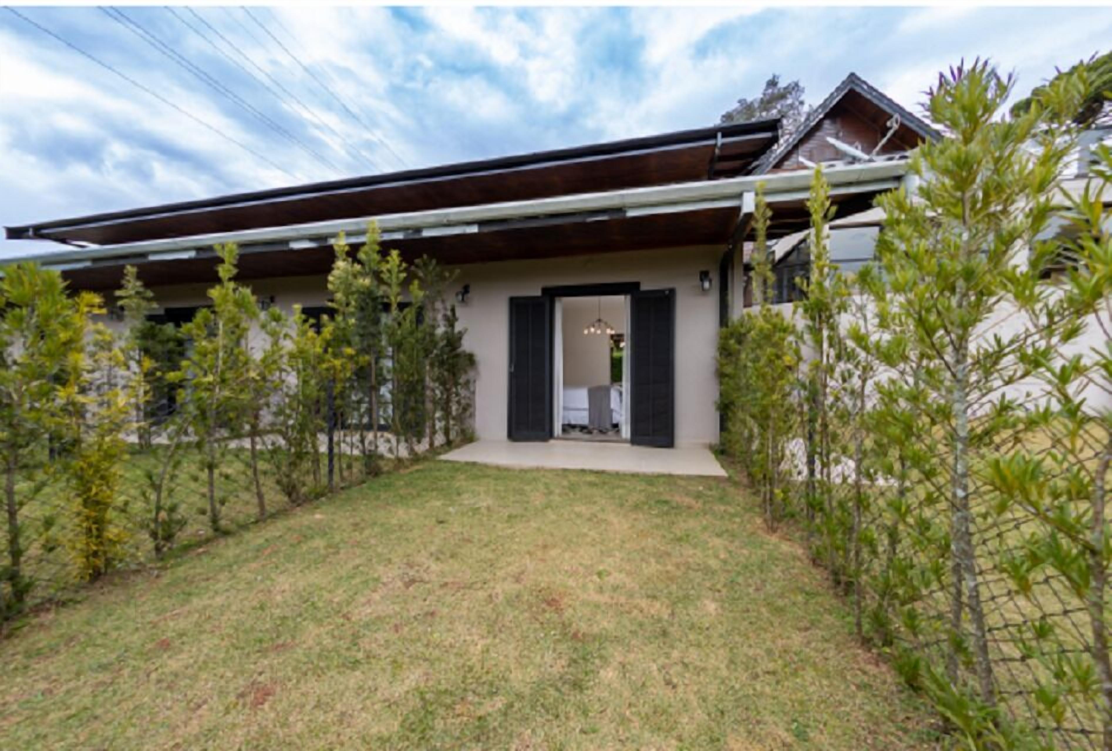 A modern house with a sloped roof, a front entrance with a door, and a small front yard with grass and young trees.