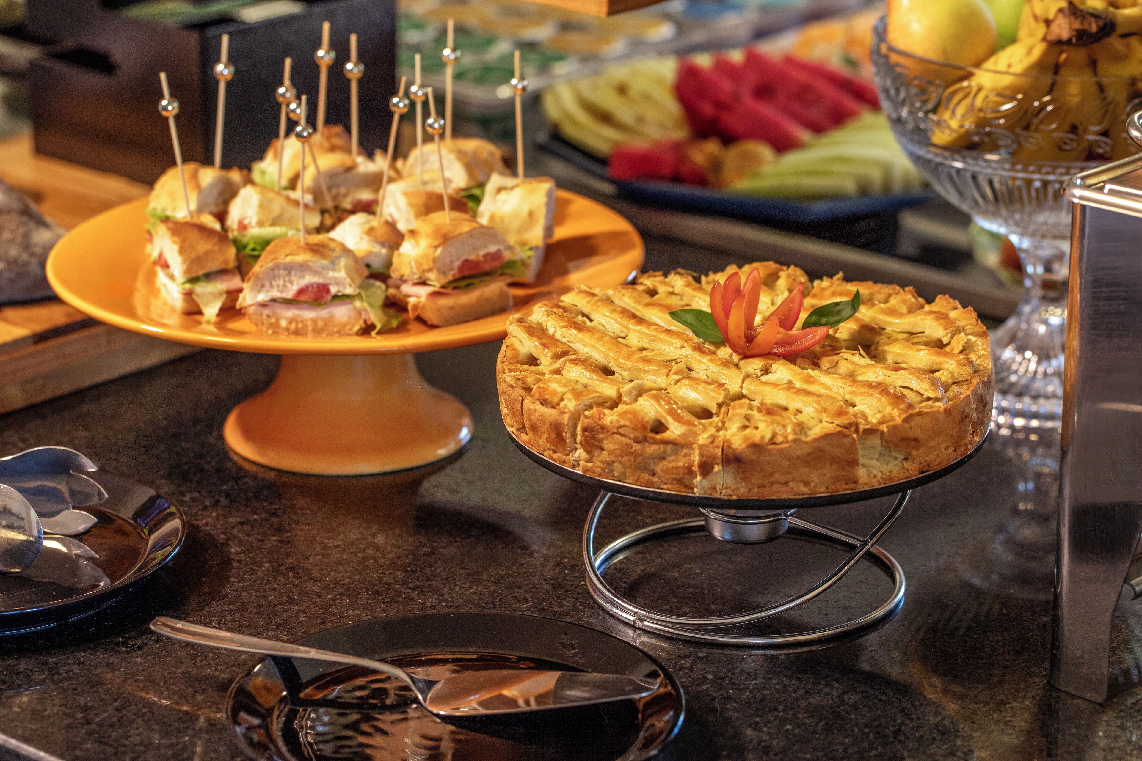 A buffet table with various food items including sandwiches, a cake, and fruit.