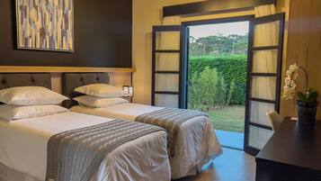 A hotel room with two beds, a desk, and a view of the outdoors.