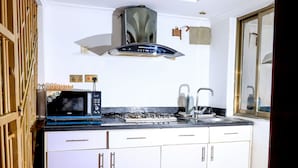 A compact kitchen with white cabinets, a black microwave, a gas stove, and a stainless steel sink.