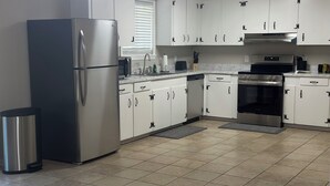 A modern kitchen with white cabinets, stainless steel appliances, and a tiled floor. - 3BR Midtown Stay! Located on USM Campus!!  Perfect for Game Days and Getaways (Hattiesburg)
