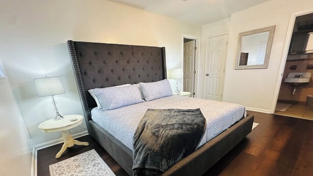 A bedroom with a large bed, a bedside table with a lamp, a starfish decoration, a rug, and a mirror on the wall. - 3BR Midtown Stay! Located on USM Campus!!  Perfect for Game Days and Getaways (Hattiesburg)