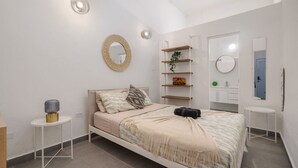 A modern bedroom with a bed, bedside tables, a mirror, and a built-in shelf with decorative items. - Luz Collection 3bedroom San Juan (San Juan)