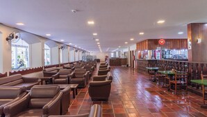 A spacious indoor area with rows of leather chairs and tables, a bar area with wooden stools, and a tiled floor. - Cavalinho Branco Flat Para 4 Pessoas c Piscina (Águas de Lindóia)