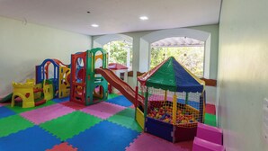 A playroom with colorful play structures, a ball pit, and a window providing natural light. - Cavalinho Branco Flat Para 4 Pessoas c Piscina (Águas de Lindóia)