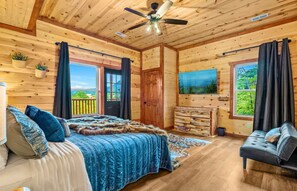 Un dormitorio de cabaña de madera con una cama, un aparador, un sofá y un ventilador de techo.