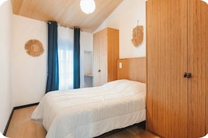 A bedroom with a bed, wooden wardrobe, and a circular wall decoration.