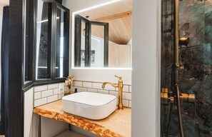 Ein Badezimmer mit einem weißen Waschbecken, einem goldenen Wasserhahn und einem großen Spiegel.