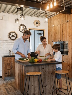 A modern kitchen with a central island, wooden cabinets, and a stainless steel oven. - Le Chai des Tortues · Character home · Beach 250 m (Rivedoux-Plage)