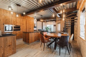 A modern kitchen with wooden cabinetry, built-in appliances, and a central island with seating. - Le Chai des Tortues · Character home · Beach 250 m (Rivedoux-Plage)