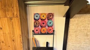 Une pièce d’angle avec un bureau en bois, une chaise noire, un canapé noir et une étagère murale où sont disposés des beignets colorés.