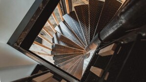 A spiral staircase with a black handrail and a textured floor. - Le Chai des Tortues · Character home · Beach 250 m (Rivedoux-Plage)