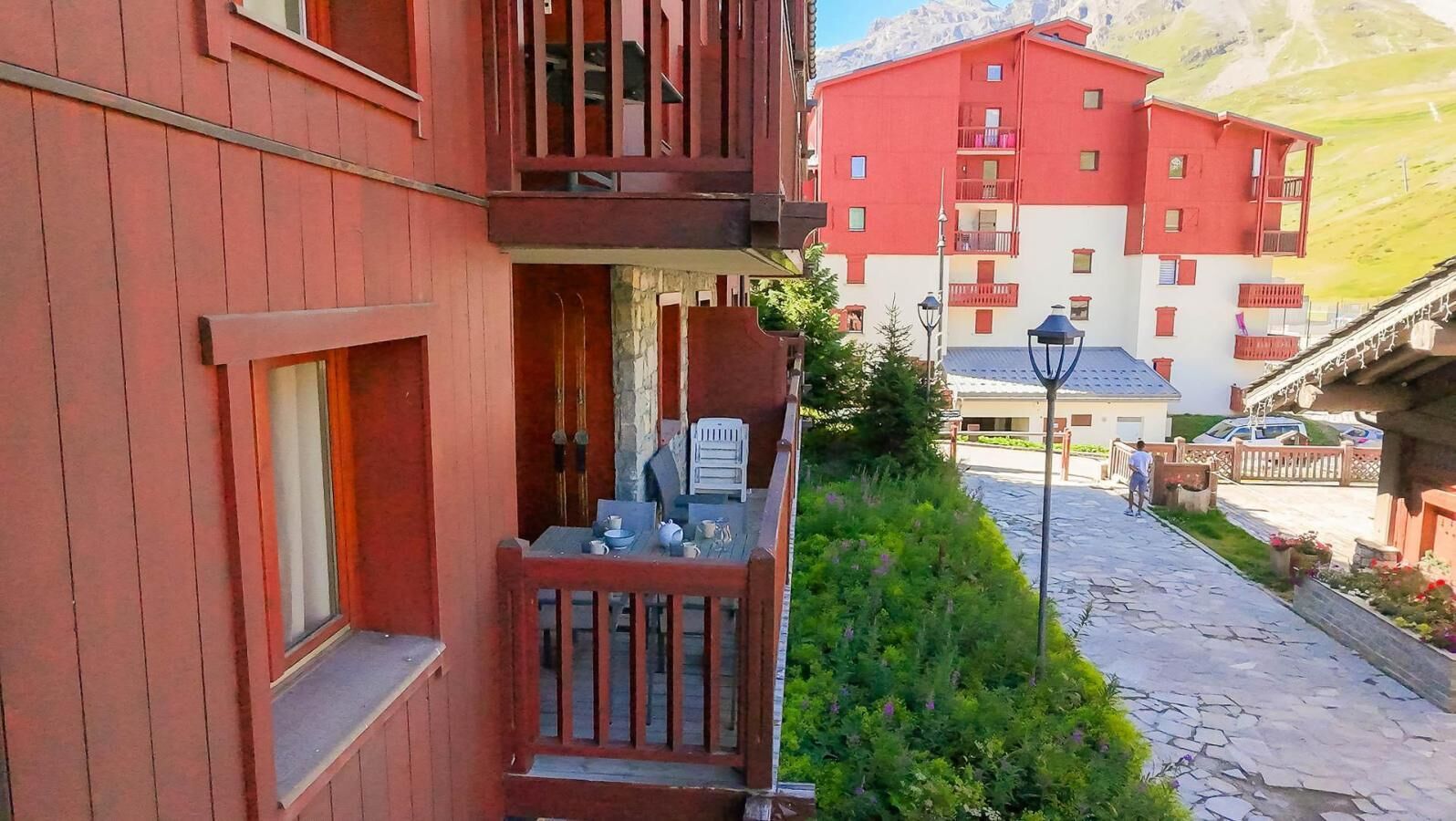 Un edificio rojo con un balcón, un camino de piedra y una persona caminando.