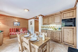 A cozy wooden cabin with a dining area, a kitchen with wooden cabinets, and a red plaid sofa with a teddy bear. - Fitness, swimming pool, sauna, hammam, terrace, parking, tv, 34m², Champagny-en-Vanoise (Champagny-en-Vanoise)