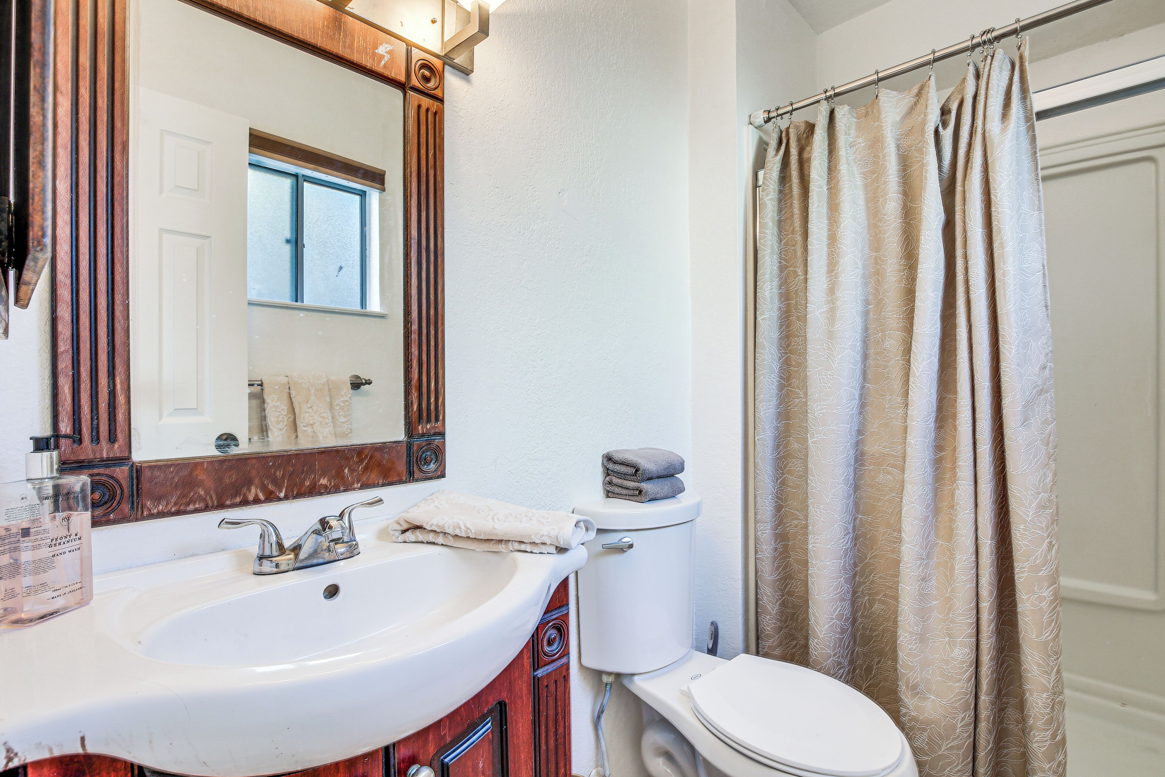 A bathroom with a white sink, a mirror, a toilet, and a shower curtain.