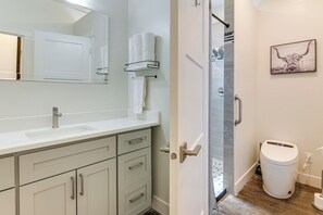 Un baño moderno con lavamanos, espejo y toallero blancos.