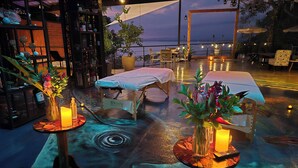 Um terraço com mesas, cadeiras e vista para o mar.