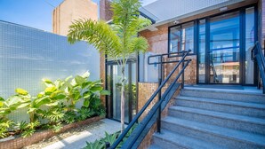 Un edificio moderno con entrada de vidrio, una escalera y diversas plantas de interior.