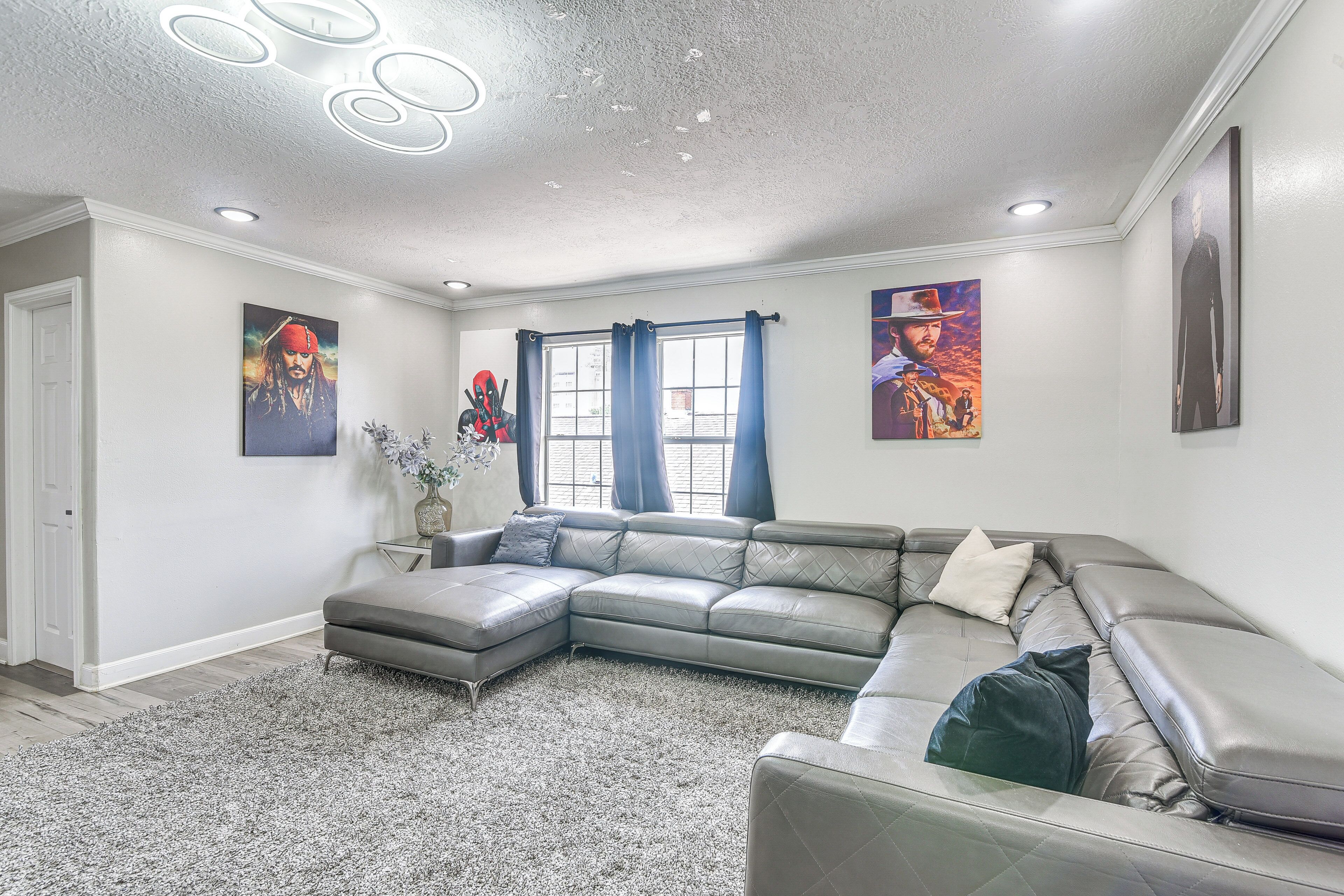 A modern living room with a sectional sofa, a grey rug, and artwork on the walls.