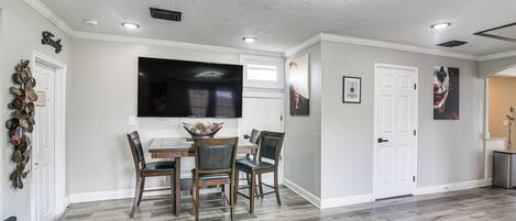 A dining area with a table, chairs, and a TV mounted on the wall.