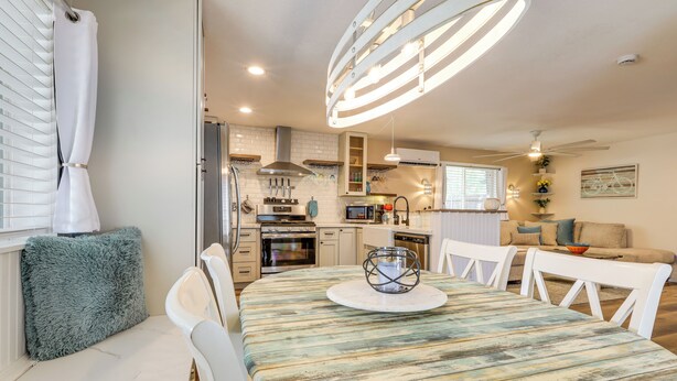 A modern kitchen with white cabinets, a central island, and a dining area with a round table and white chairs. - Less Than a Mile to Forest Roads/Trails (Flagstaff)
