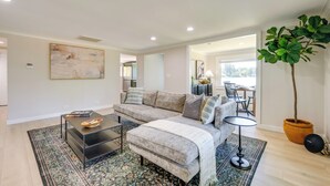 A modern living room with a sectional sofa, a glass coffee table, and a large potted plant.