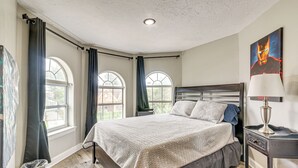 Een slaapkamer met een groot bed, een nachtkastje, een lamp en een schilderij aan de muur.