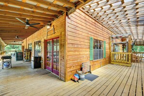 A wooden cabin with a covered porch, a refrigerator, a grill, and a door with a red frame. - Creek Access, Games: Family-Friendly Royal Retreat (Royal)