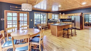 A spacious kitchen with wooden cabinets, a central island with stools, and a dining area with a round table and chairs. - Creek Access, Games: Family-Friendly Royal Retreat (Royal)