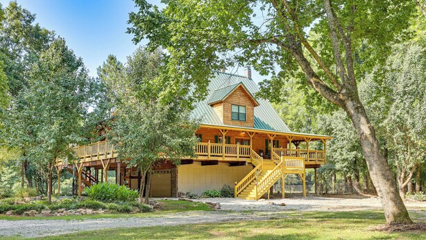 A cabin with a wooden deck, a covered porch, and a staircase leading to a second-story balcony. - Creek Access, Games: Family-Friendly Royal Retreat (Royal)