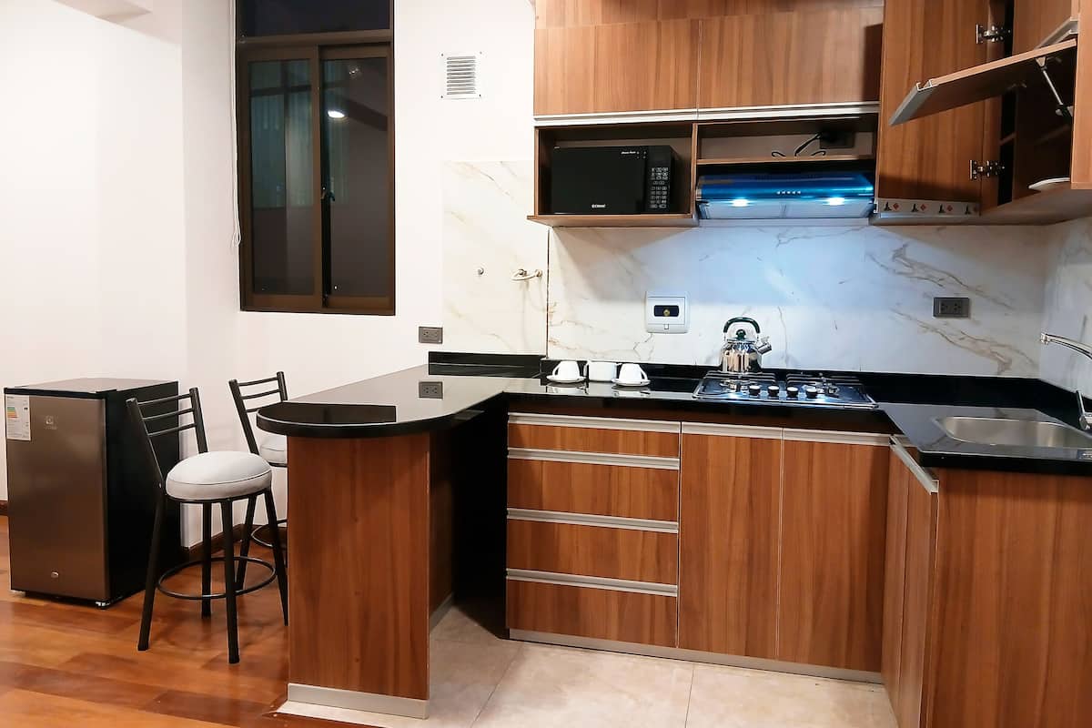 Una cocina compacta con armarios de madera, microondas integrado y cocina a gas.