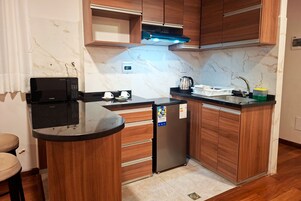 Una cocina compacta equipada con microondas, refrigerador, lavaplatos y armarios de madera.