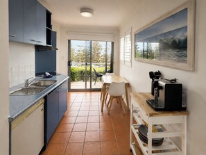 A modern kitchen with a sink, stove, and dining area with chairs.