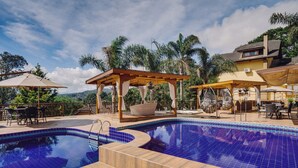 Una piscina con cubierta de madera, asientos exteriores y un pabellón.