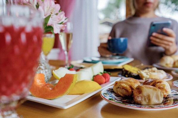 A breakfast setting with a plate of fruit, pastries, and a glass of juice. - Carícia do Vento Pousada Boutique (Camanducaia)