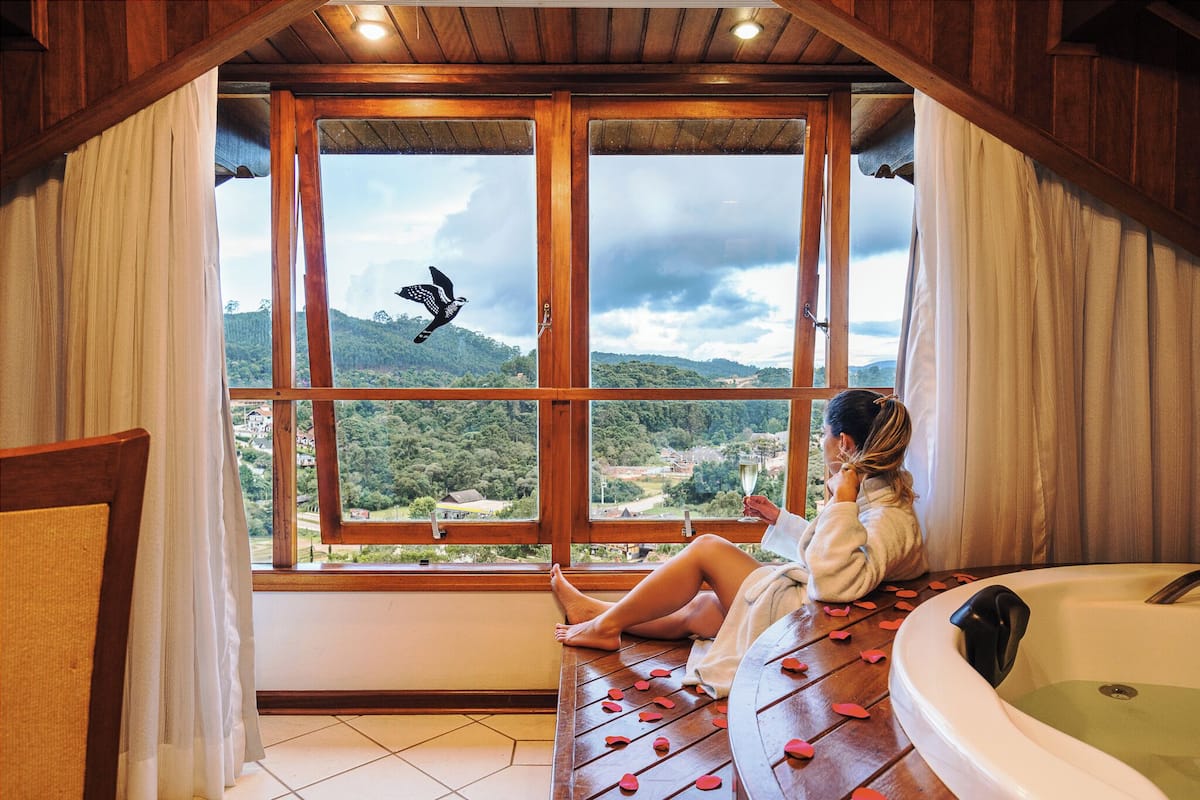 Una mujer descansando junto a una ventana con vista a un paisaje montañoso.
