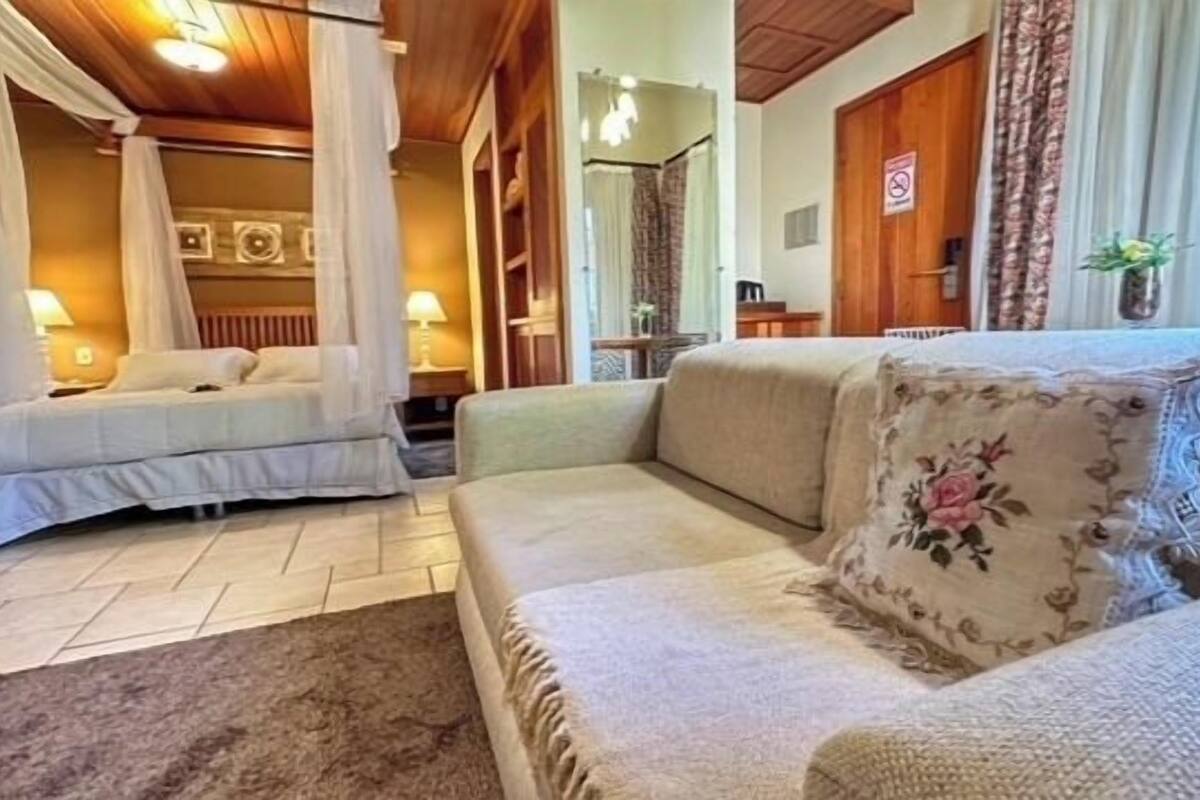 Un dormitorio con una cama, un sofá y una mesita de noche.
