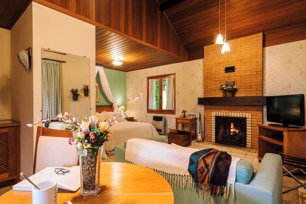 Una habitación acogedora con chimenea, televisión y zona de comedor con mesa y sillas.