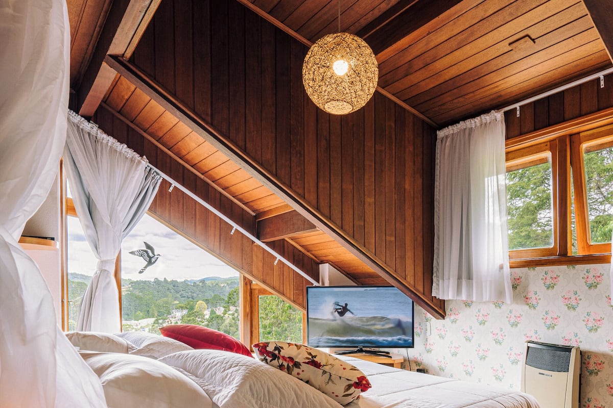 Un dormitorio con cama, televisor y ventana con vistas a zonas verdes.