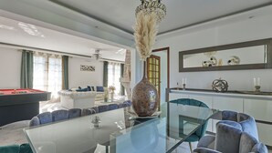Un salón moderno con una mesa de comedor de vidrio, asientos cómodos y objetos decorativos.