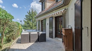 Un patio con un conjunto de asientos y un edificio con tejado de baldosas y grandes ventanales.