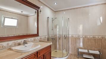 Un baño con lavamanos, espejo, ducha y toallero.