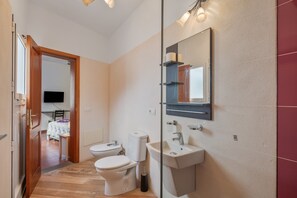 Een badkamer met toilet, wastafel en spiegel.