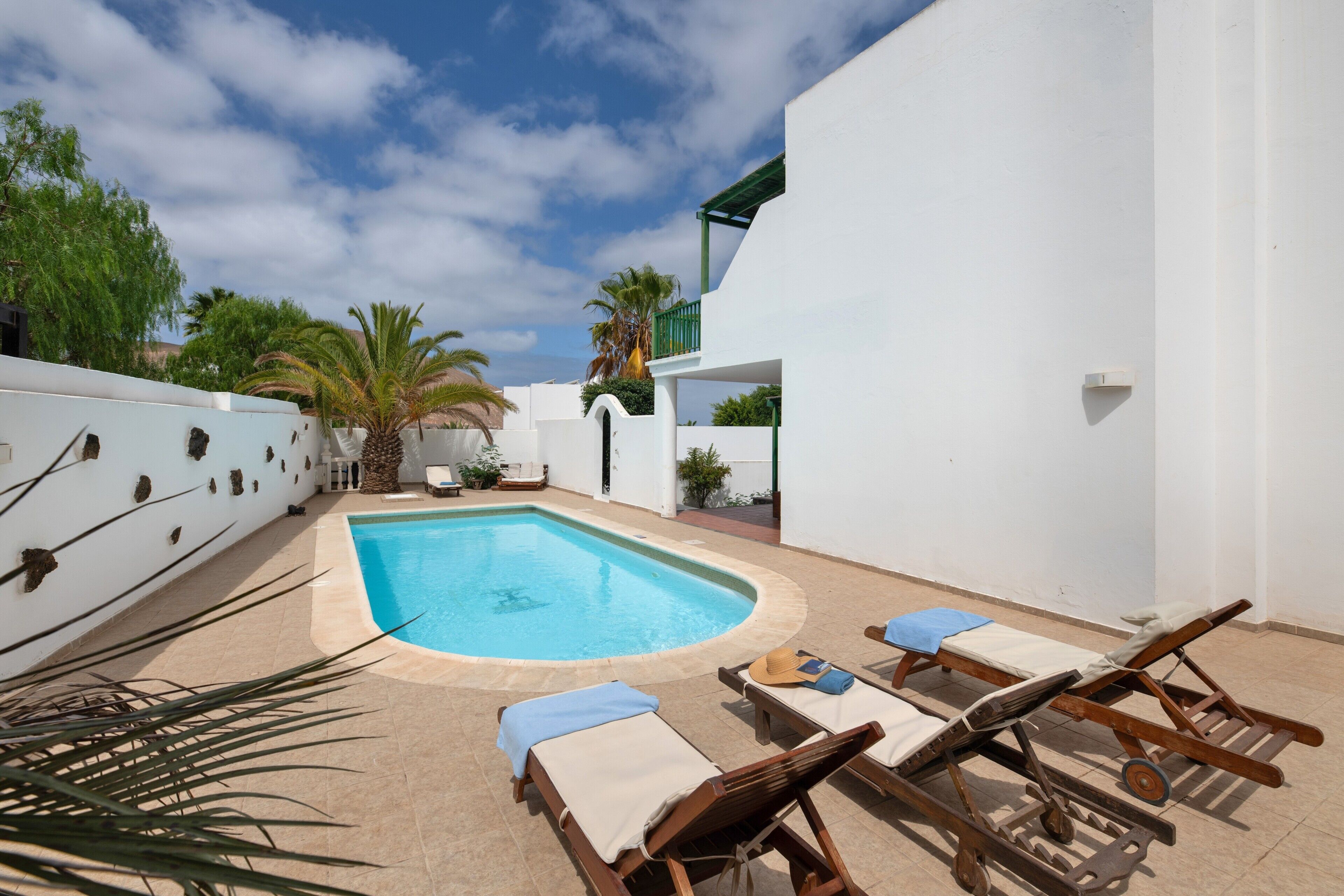A swimming pool with lounge chairs and a white building.