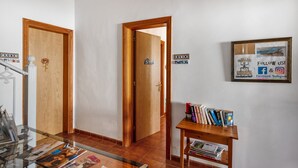 Un pasillo con puertas de madera, una mesa de vidrio con revistas y una pequeña mesa de madera con libros.