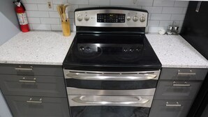 Una cocina con estufa negra, horno de acero inoxidable y armarios grises.