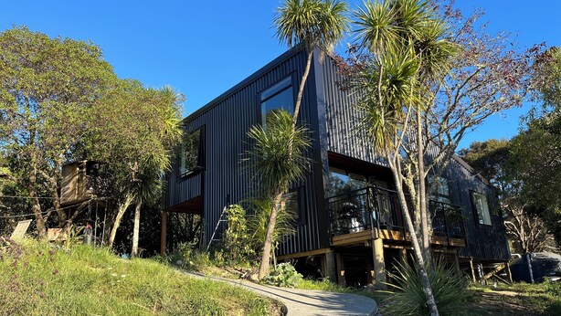 A modern building with a sloped roof, surrounded by trees and a pathway.