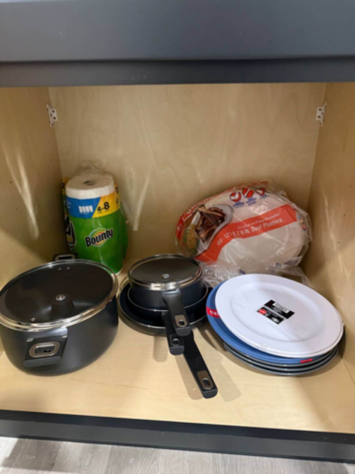 A kitchen with a stove, pots, a rolling pin, and a stack of plates.