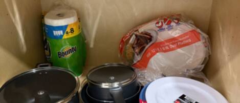 A kitchen with a stove, pots, a rolling pin, and a stack of plates.