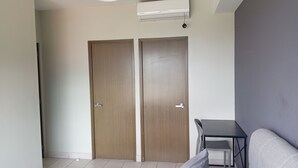 Een kamer met twee houten deuren, een tafeltje met stoelen, en een airconditioning op de muur.